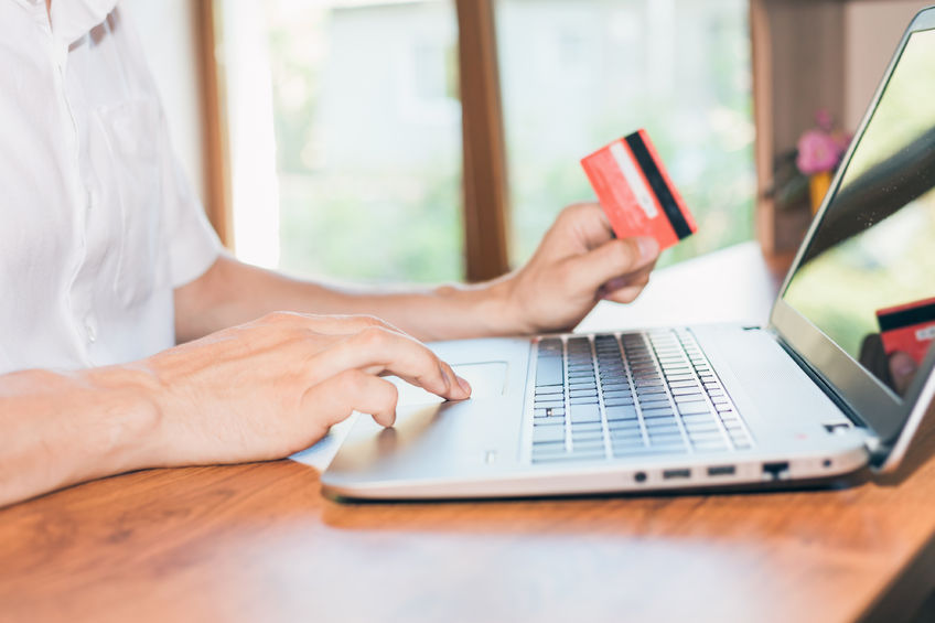 affiliate-marketing hands holding credit card next to a laptop